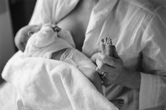 Eine Frau die ihr Baby stillt und dabei den Fuß des Babys in der Hand hält in schwarz-weiß
