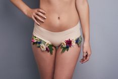 Frau in Slip mit Blumen, die zur Seite unter dem Slip hervortreten