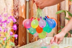 Mann hält viele gefüllte Wasserbomben in der Hand