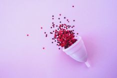 Rosane Menstruationstasse mit Sternenkonfetti auf rosa Hintergrund