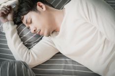 Mann, der im mit geschlossenen Augen im Bett liegt