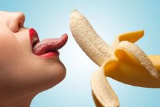 Frau leckt an einer halb geschälten Banane