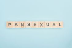 Holzbuchstaben mit der Aufschrift "Pansexual" vor hellblauem Hintergrund