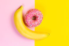 Banane und Donut auf rosa-gelben Hintergrund