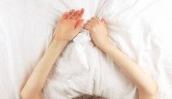 Zwei weibliche Hände greifen in die Bettdecke
