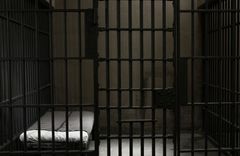 Eine triste Gefängniszelle, in der nur ein Bett steht.