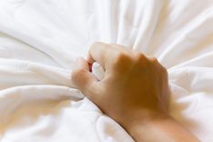 Hand krallt sich in eine Bettdecke