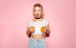Junge Frau hält sich 2 Donuts vor die Brüste