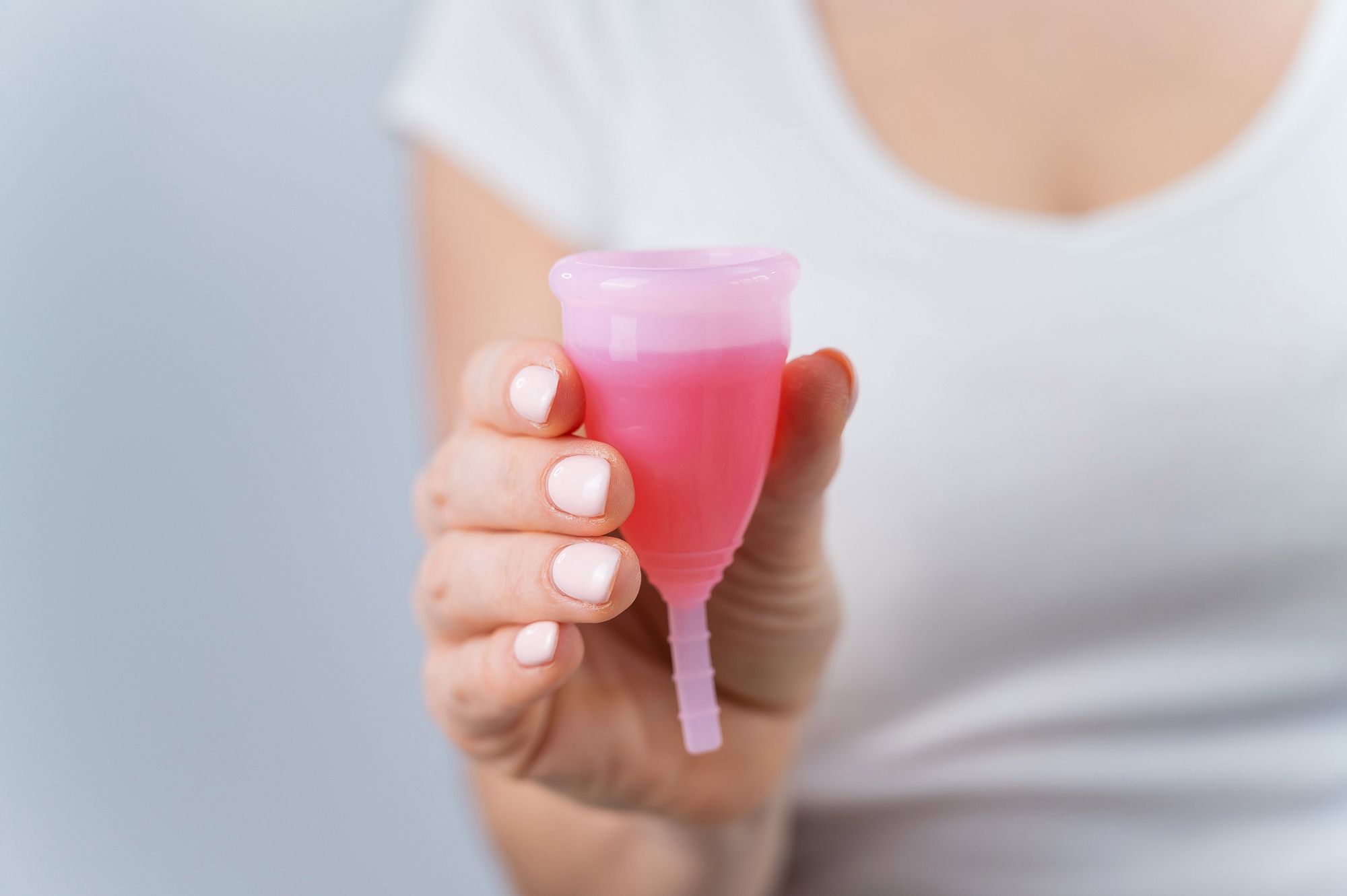 Frau hält gefüllte Menstruationstasse in der Hand