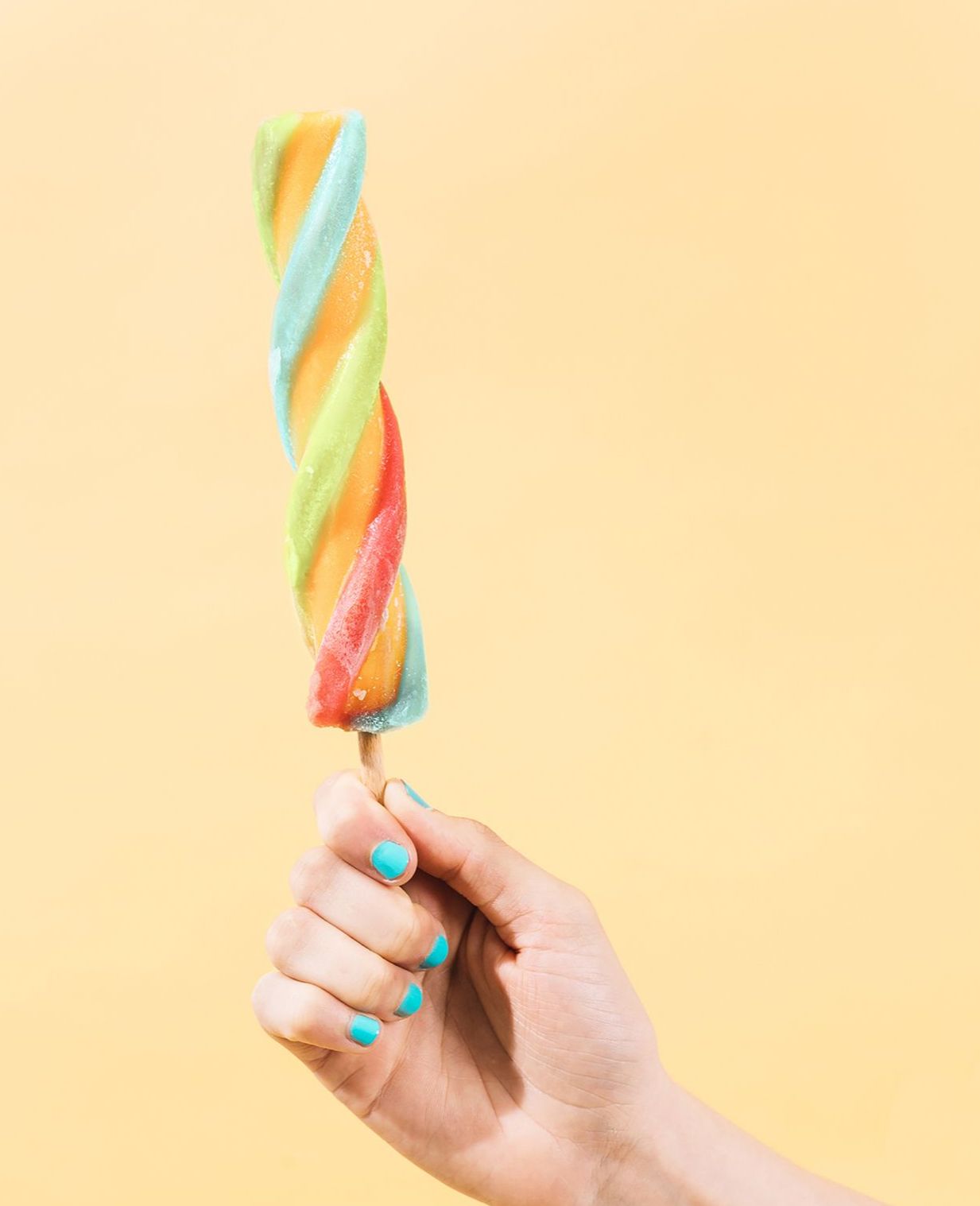 Frau hält ein buntes Eis am Stiel in der Hand