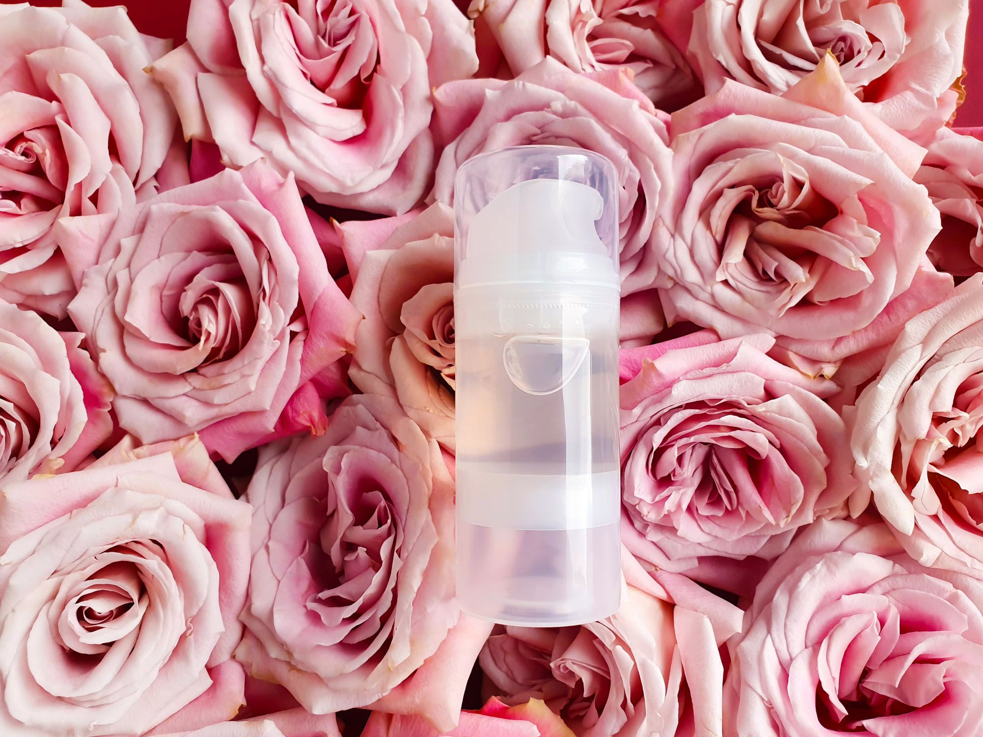 Gleitgel in einem transparenten Pumpspender, der auf rosa Rosen liegt